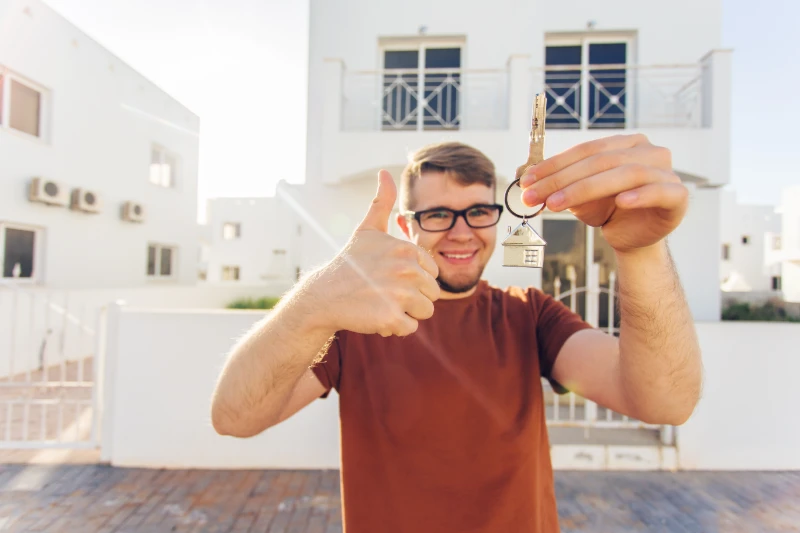 Man holding keys outside new home.